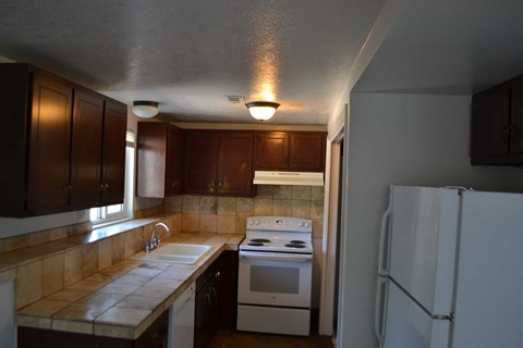 A kitchen with brown cabinets and a white stove.