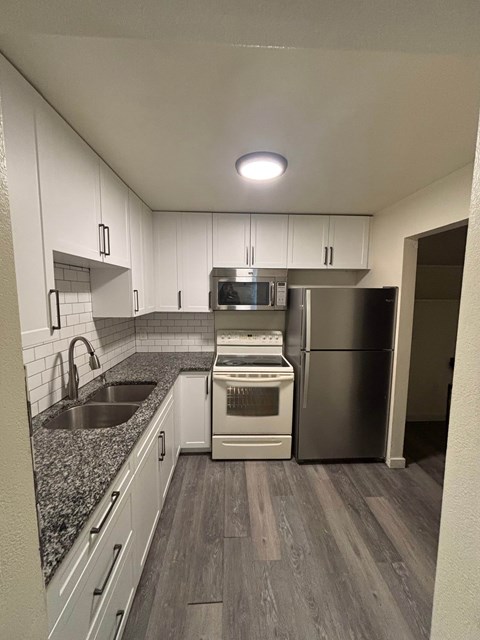 A kitchen with a sink, stove, and refrigerator.