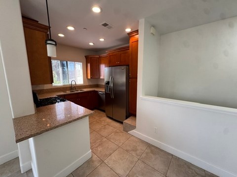 A kitchen with a refrigerator, sink, and cabinets.