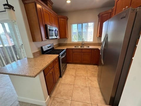 A kitchen with a refrigerator, microwave, and oven.