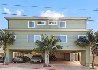 A two-story house with a garage and a palm tree in front.