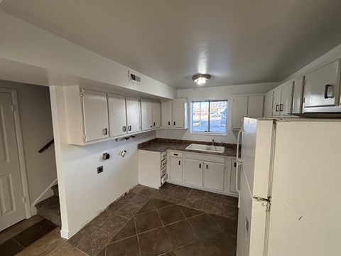 A kitchen with white cabinets and a tiled floor.