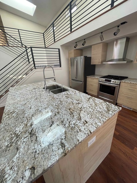 A kitchen with a granite countertop and stainless steel appliances.