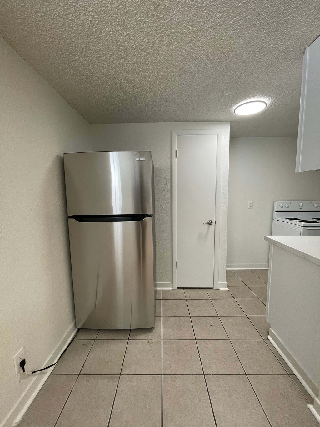 A kitchen with a stainless steel refrigerator and a white door.