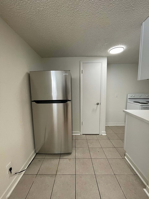 A kitchen with a stainless steel refrigerator and a white door.