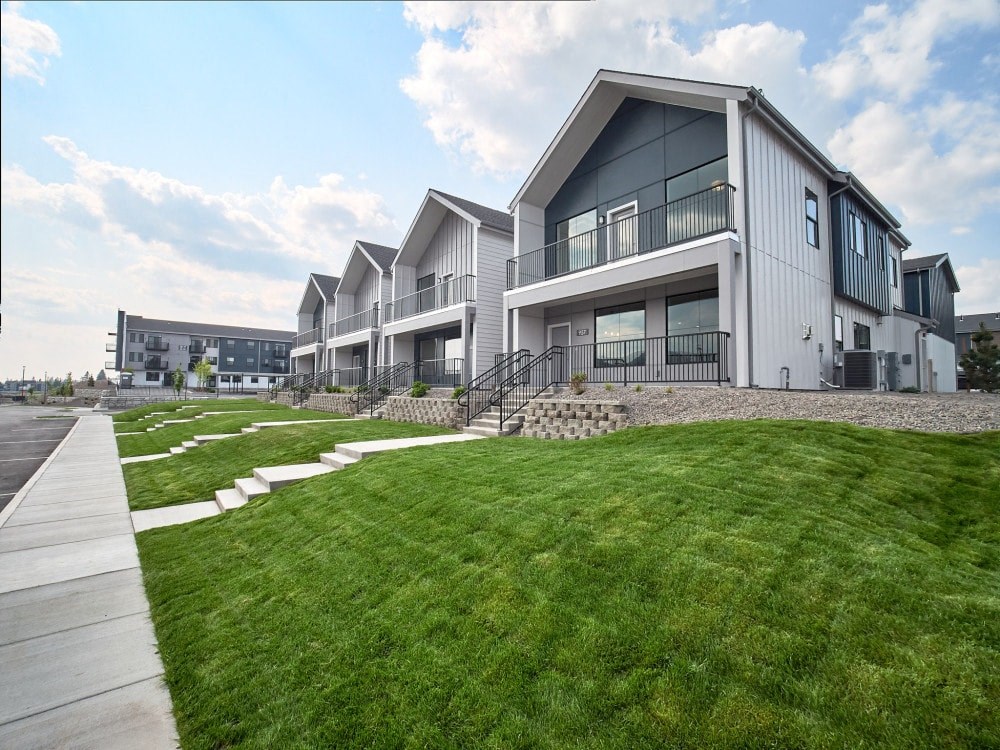 a row of houses with green grass and a sidewalk