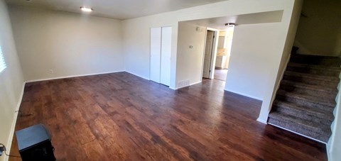 an empty living room with wooden floors and a staircase