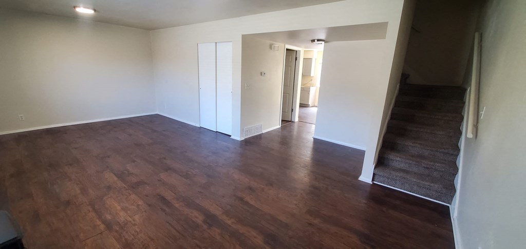 an empty living room with wood flooring and white walls