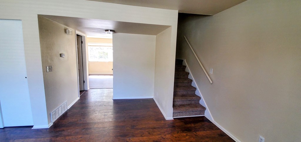 a view of a staircase in a house with white walls and wood floors