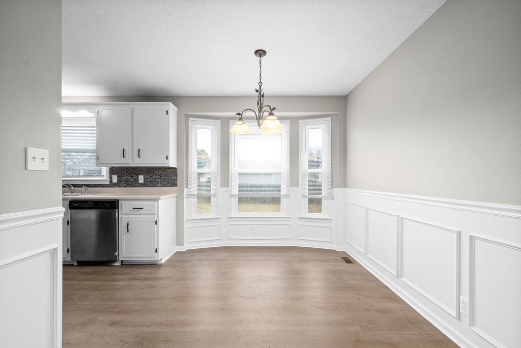 an empty kitchen with white cabinets and a window