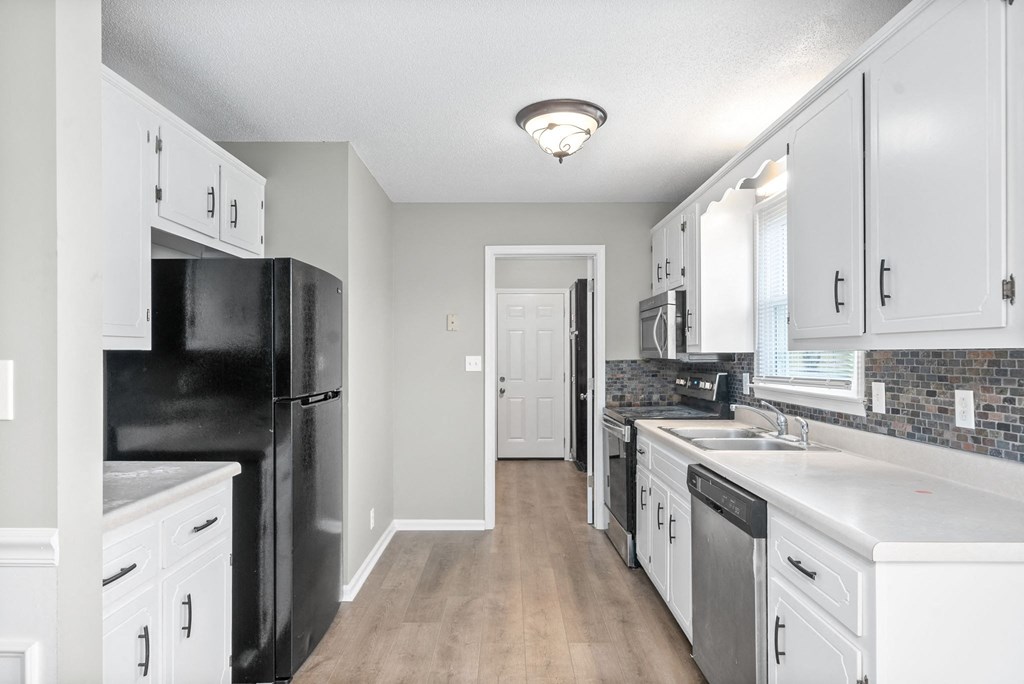 a kitchen with white cabinets and a black refrigerator