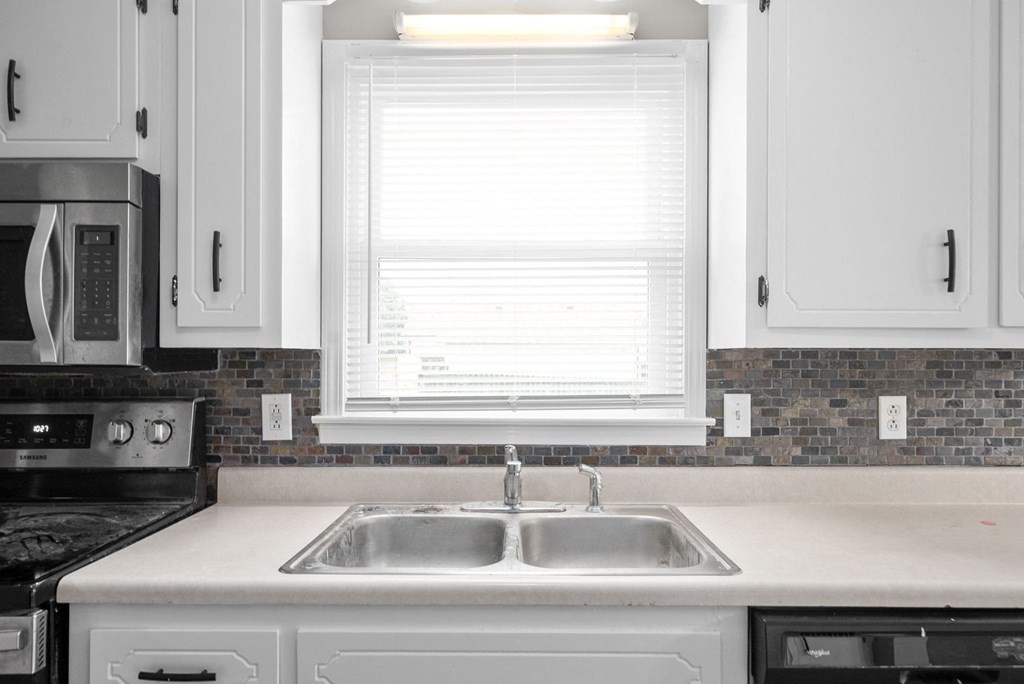 a white kitchen with a sink and a window