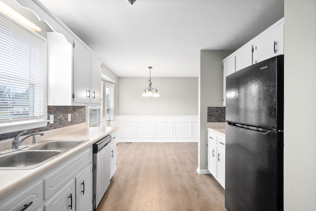 an empty kitchen with white cabinets and a black refrigerator