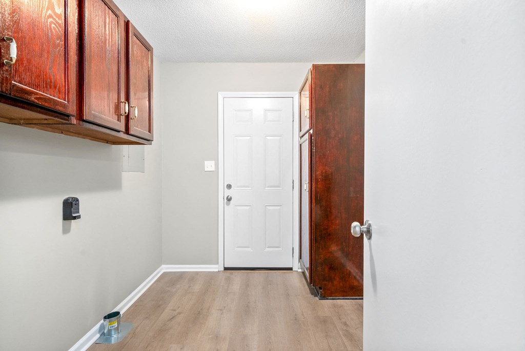 an empty room with a white door and wooden floors and cabinets