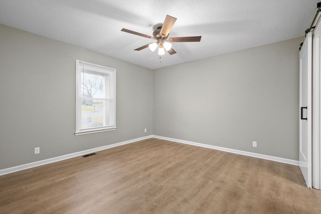 an empty living room with a ceiling fan and a window