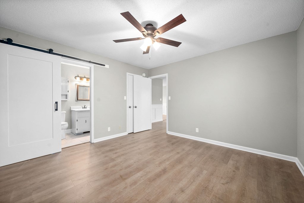 an empty living room with a ceiling fan and a bathroom
