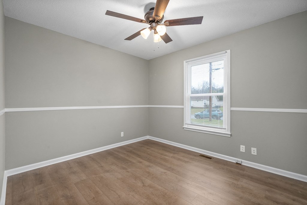 an empty living room with a ceiling fan and a window