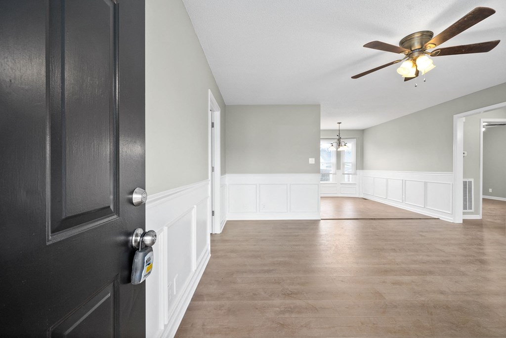 an empty living room with a black door and a ceiling fan