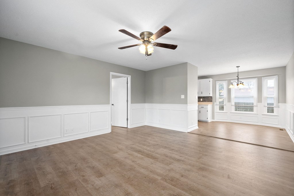 an empty living room with a ceiling fan