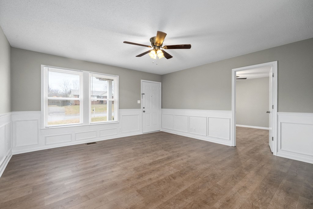 an empty living room with a ceiling fan