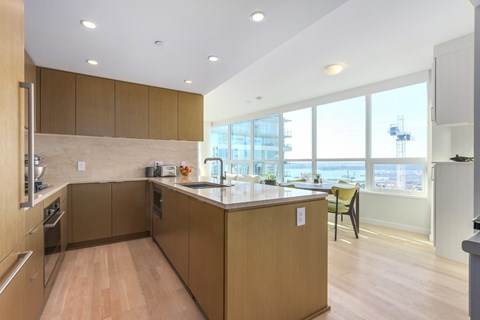 A kitchen with wooden cabinets and a countertop with a chair.