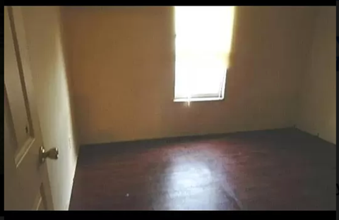 an empty room with a window and a wooden floor