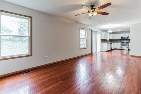 an empty living room with wood floors and a ceiling fan