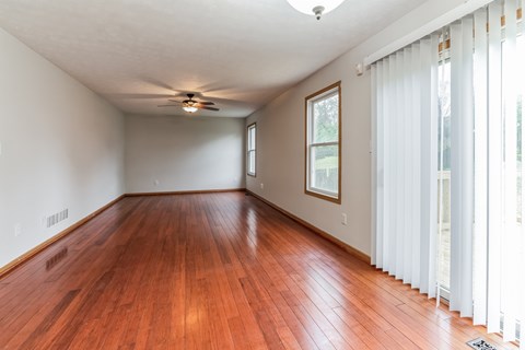 an empty living room with wood floors and a ceiling fan
