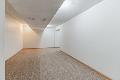 a room with white walls and carpet and a door in the corner