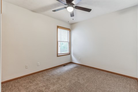 an empty living room with a ceiling fan and a window