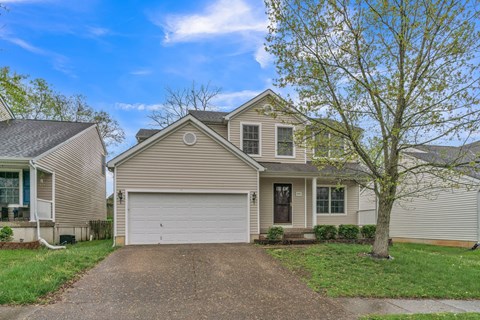 a tan house with a white garage door on a driveway