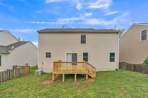 a backyard with a wooden deck in front of a house