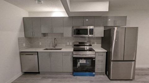 A kitchen with stainless steel appliances and a blue box on the floor.