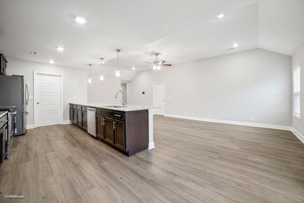 an open kitchen and living room with a refrigerator and a sink
