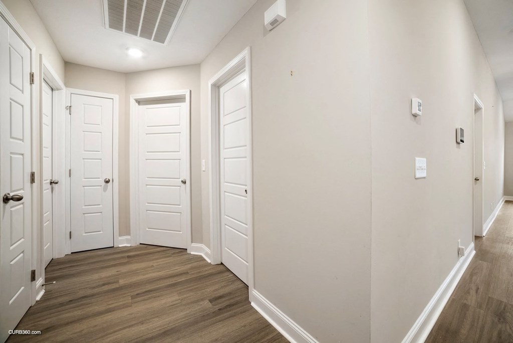 a hallway with white doors and white walls and wood floors