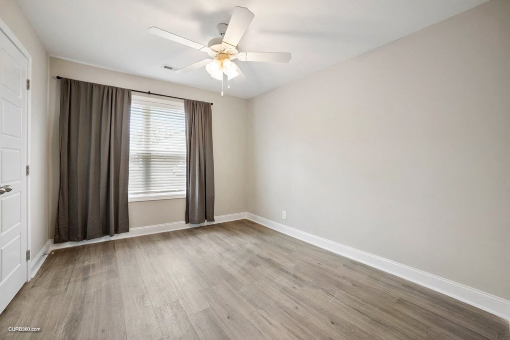 an empty living room with a ceiling fan and a window