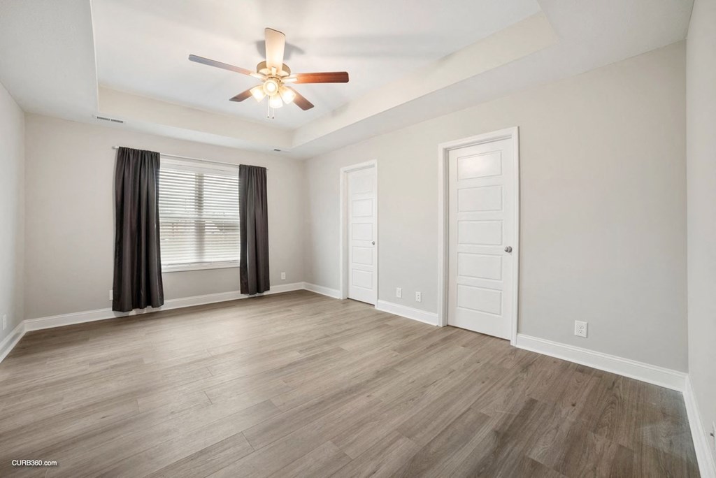 an empty living room with a ceiling fan and a window