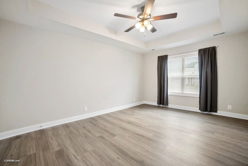 an empty living room with a ceiling fan and a window