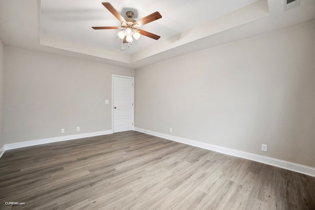 an empty living room with wood flooring and a ceiling fan