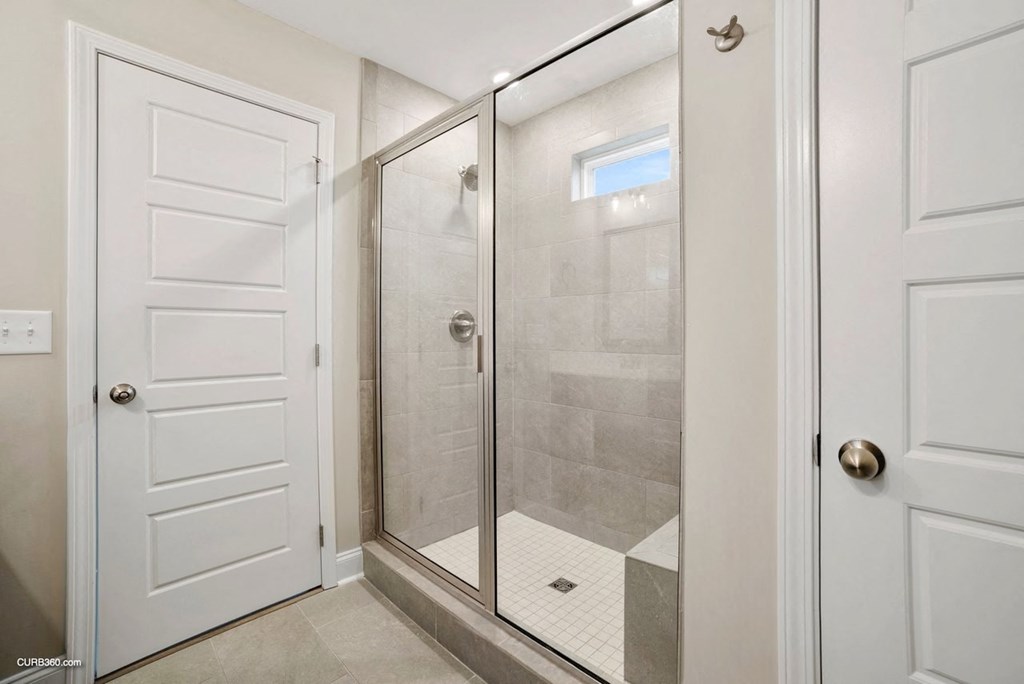 a bathroom with a shower and a white door
