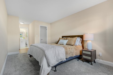A bedroom with a bed, nightstand, and lamp.