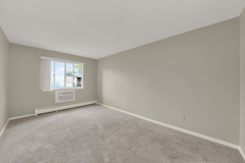 A room with a carpeted floor and a window.