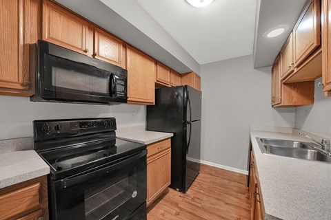 A kitchen with black appliances and wooden cabinets.