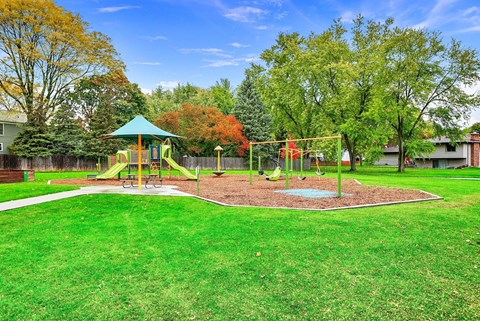 A playground with a green swing set and a red slide.