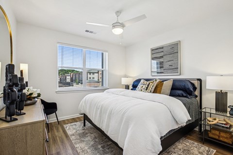 A bedroom with a large bed and a window overlooking a cityscape.