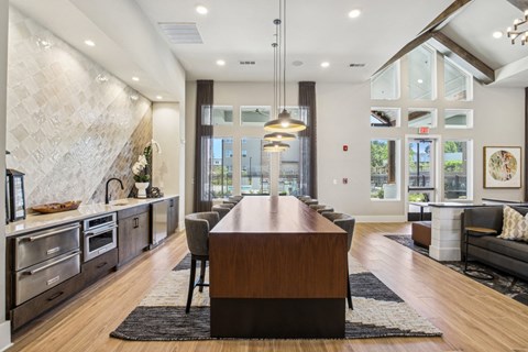 A modern kitchen with a long wooden island in the middle.