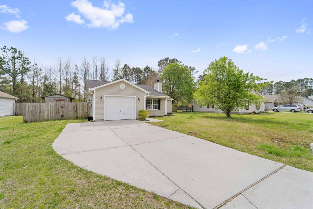 A house with a garage is surrounded by a fence and trees.