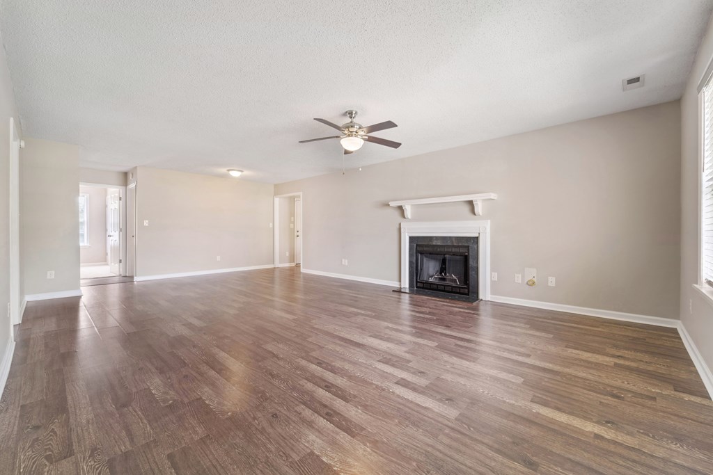 A spacious room with a fireplace and wood flooring.
