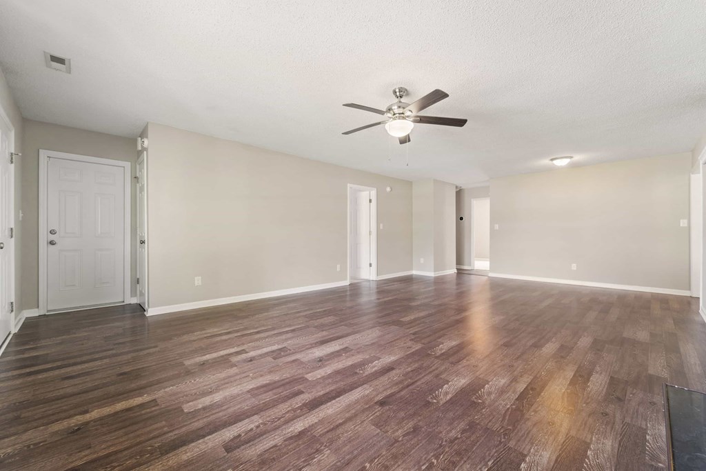 A room with a ceiling fan and hardwood floors.