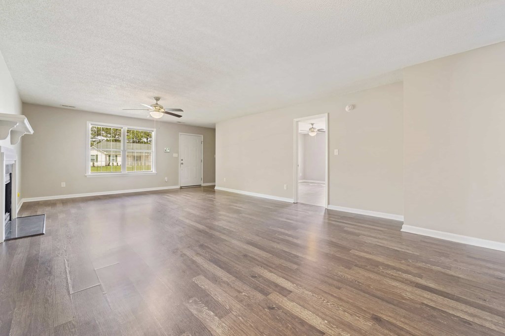 A spacious room with wooden flooring and a ceiling fan.